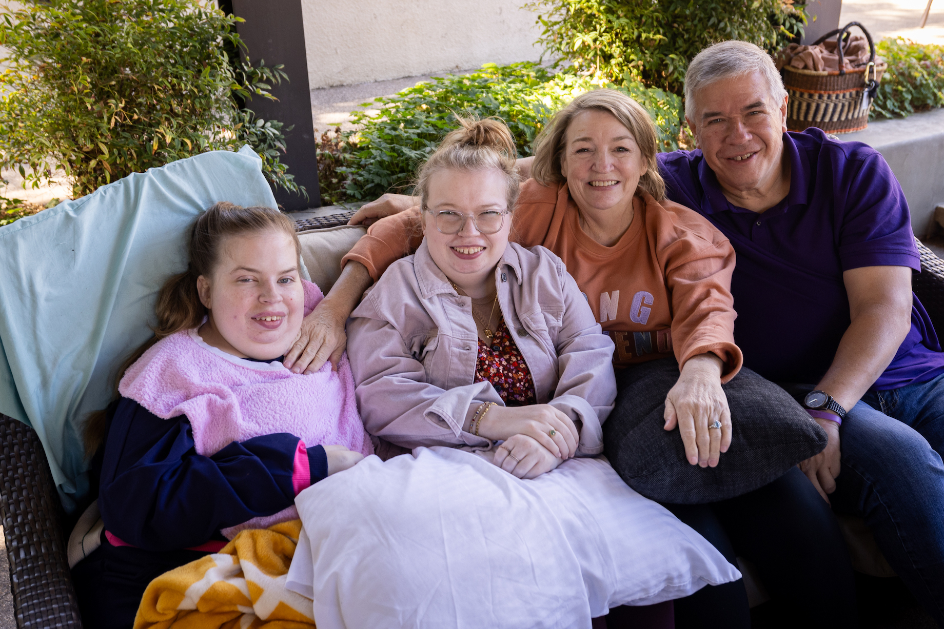 a family of four sits together on an outdoor sofa